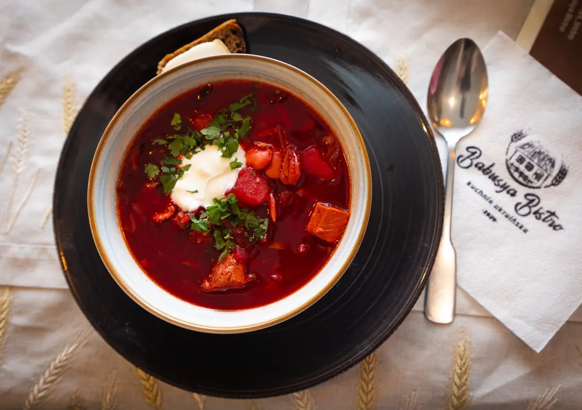Barszcz ukraiński ze śmietaną, obok serwetka z logo Babusya Bistro
