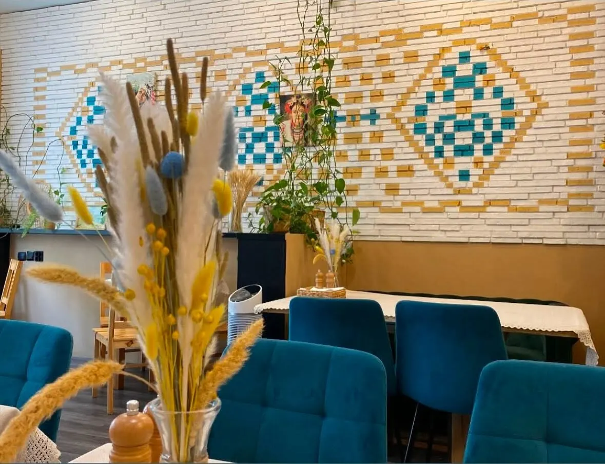 Sala Babusya Bistro: stoły nakryte obrusami, zielone ławy, kwiaty w wazonie